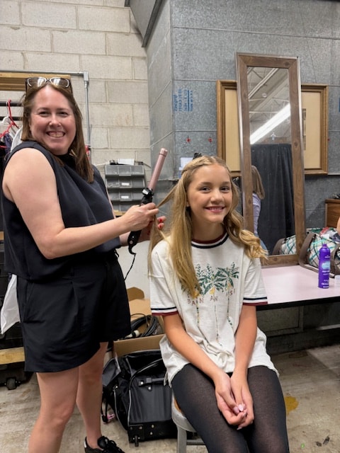 Dancer getting hair curled backstage before a Fitzpatrick performance