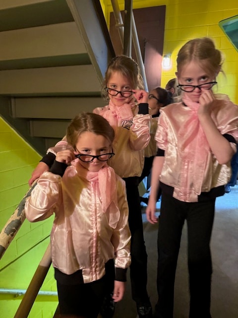 Young dancers in Pink Ladies costumes backstage before the show