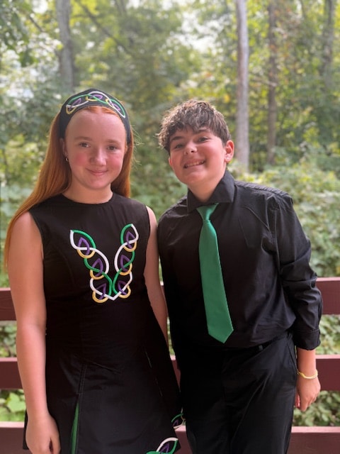 Young dancer hugging an older dancer in Celtic costumes, both smiling