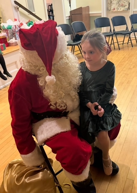 Young dancer in a green dress posing with Santa Claus at the Fitzpatrick holiday party