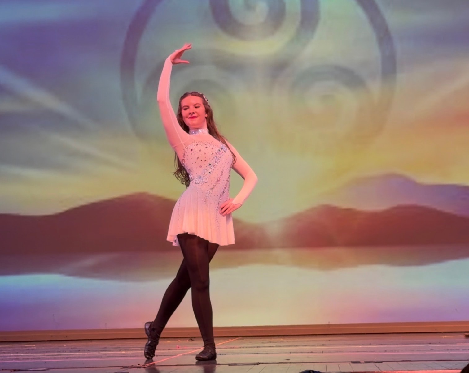 Solo Irish dancer performing on stage with Celtic backdrop