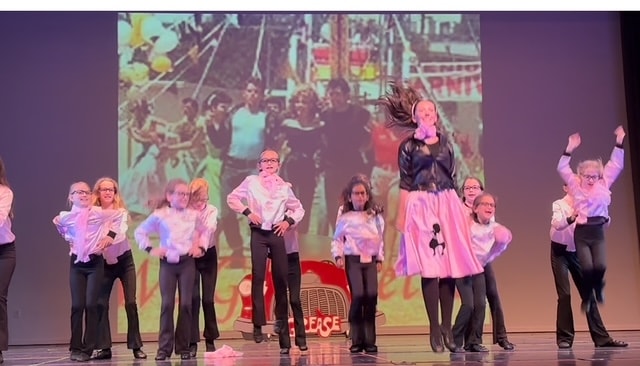 Dancers performing a Grease-themed number on stage