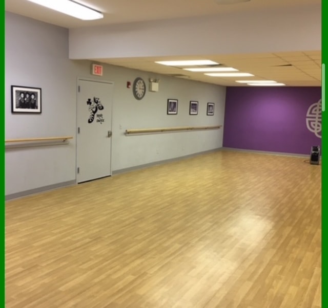 Second studio room with Celtic knot mural, barre, and hardwood floor